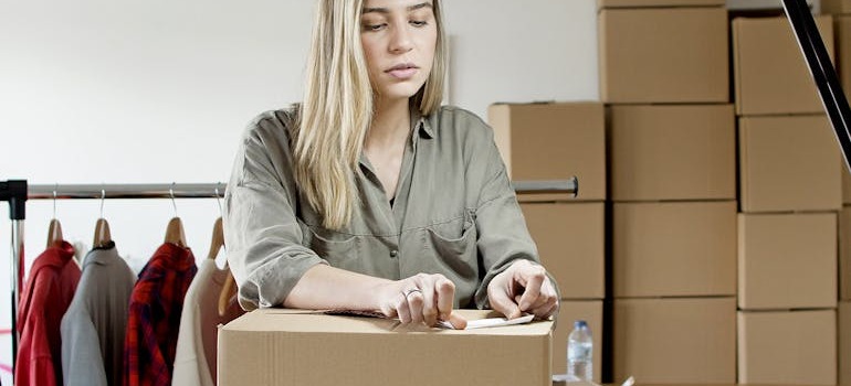 A woman puts a sticker on a moving box