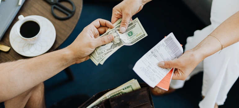 A woman paying for something after researching the most common moving scams in Long Island CIty.